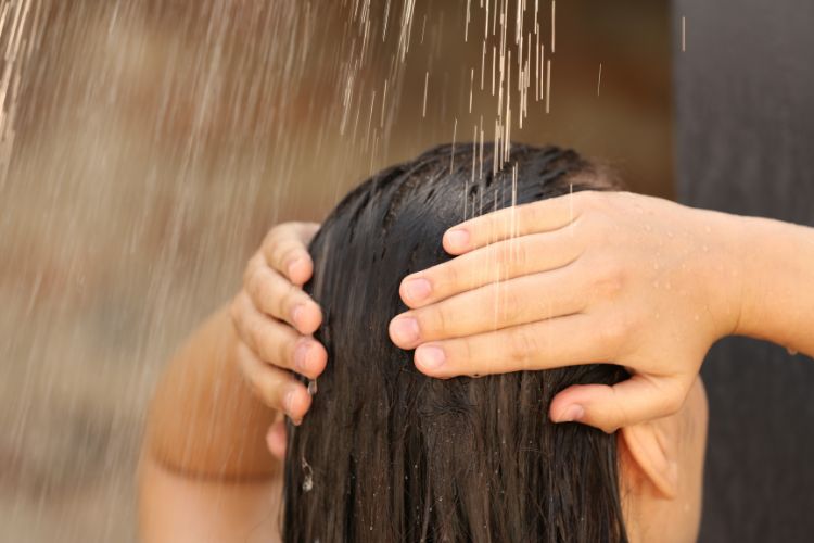 mujer lavandose el pelo en verano en ducha